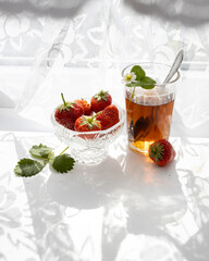 Cup of tea and wild strawberries on a white lace background