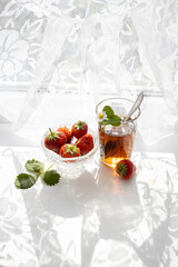 Cup of tea and wild strawberries on a white lace background