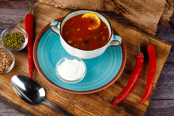 Traditional Ukrainian Russian borscht in a plate. A plate of red beet borscht on a dark table. Beetroot garden Top view.