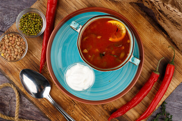 Traditional Ukrainian Russian borscht in a plate. A plate of red beet borscht on a dark table. Beetroot garden Top view.