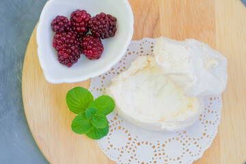 Meringue dessert with berries. Anna Pavlova cake cake with homemade blackberries and mint, sauce and figs served, on a white napkin on wooden background. Meringue tray. Close up photo of meringues.