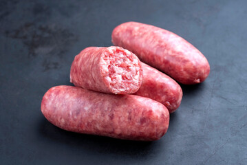 Traditional Italian raw salsiccia fresco meat sausage offered as close-up on a rustic black board with copy space