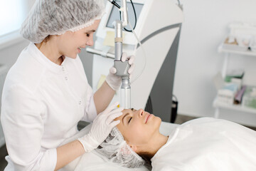 Fototapeta premium Cosmetology. Closeup Of Female Face having facial treatment in beauty salon. Cosmetic procedures in spa clinic. High quality photo