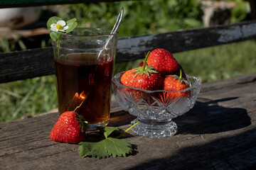 Cup of tea and wild strawberries on a wooden background