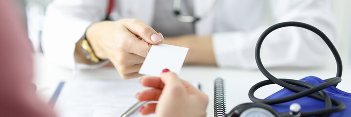 Doctor passes business card to patient in medical office.