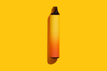 Disposable e-cigarette on yellow isolated background. The concept of modern smoking, vaping and nicotine. Top view