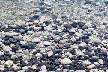 Colorful large pebbles under clear water on the beach of mediterranean sea