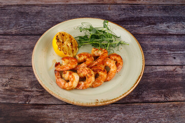 butter garlic fried shrimp sprinkled with chili and parsley on a white platter, on a wooden table