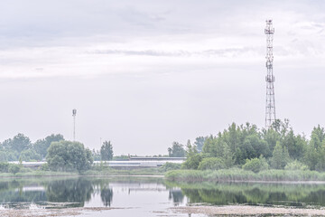 industrial zone and communication towers on the shore of the lake on a foggy morning