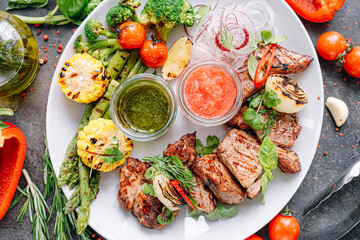 shish kebab and vegetables grilled and served on a white plate