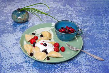 Dumplings stuffed with curd served with sour cream, strawberries and currants.