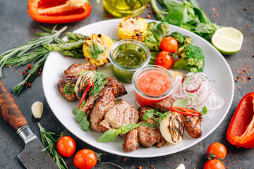 shish kebab and vegetables grilled and served on a white plate