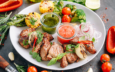 shish kebab and vegetables grilled and served on a white plate