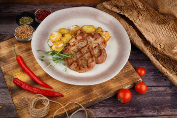 BBQ pork loin meat steak with potato. Dark background.
