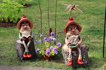 Fabulous funny gnomes made of burnt clay sitting on wooden stumps