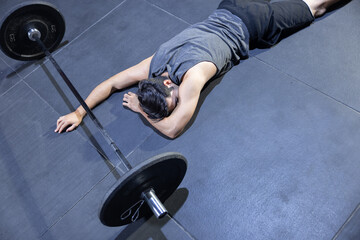 Unconcious Caucasian  Man Faint on the Gym Floor with a Barbell in Front of Him