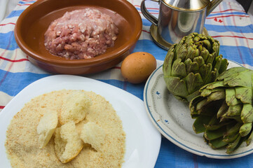 Table with the ingredients to prepare artichokes stuffed with meat