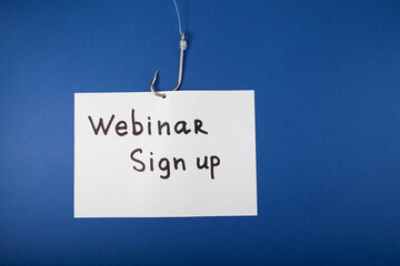 White paper sheet with inscription WEBINAR SIGN UP and fishing hook with fishing line on blue background. Design element