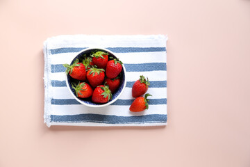 Fresh strawberries in a bowl on a pink background. Healthy food. Top view.