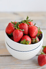 Fresh strawberries in a bowl on a wooden background. Healthy food. Side view.