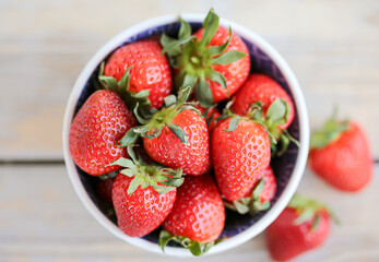 Fresh strawberries in a bowl on a wooden background. Healthy food. Top view.