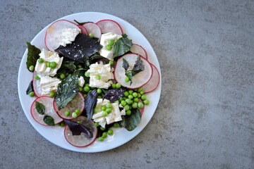 A healthy salad with fresh radishes, green peas and feta cheese. Healthy diet. Delicious fresh salad.