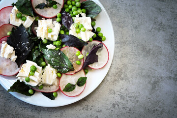 A healthy salad with fresh radishes, green peas and feta cheese. Healthy diet. Delicious fresh salad.