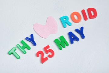 cut out from felt thyroid gland and inscription from plastic letters thyroid gland day 25 may on gray background, thyroid awareness month concept