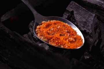 Metal spoons with various spices and seasonings on a dark background, black charcoal. Cooking spices concept. Selective focus. Low key