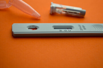 test for coronavirus on an orange background. on a matte background, a sensitive strip for coronavirus, a lancet, a container for saline. home test kit for coronavirus, a drop of blood on the test