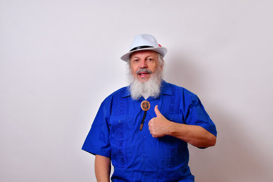 Happy Smiling Old Man With A White Fedora Hat, Blue Guayabera Shirt, And Bolo Tie Showing Thumbs Up