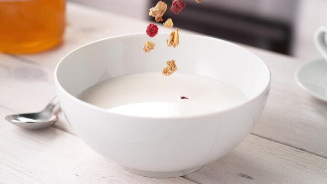 Crispy Granola Cereals Falling into White Bowl Filled with Milk in Slow Motion (Phantom Flex)