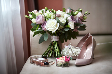 bridal accessories such as shoes, bouquet , ring and perfume lie on a table
