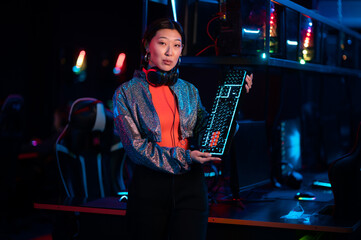 A cute female gamer from the chinese women's esports team poses with a new comfortable gaming keyboard in her hands