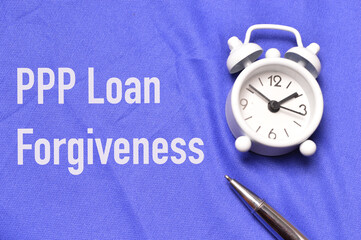 Top view of clock and pen over blue background written with PPP LOAN FORGIVENESS.