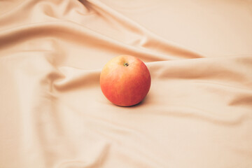 Red-yellow apple on beige satin. Minimal design.