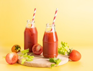 glass bottle of tomato juice, lime with fresh bright bunch of tomatoes isolated on green background, green parsley. vegetable drink.