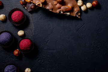 Obraz na płótnie Canvas Chocolate bar, crushed pieces of dark chocolate and nuts. Praline Chocolate sweets. Copy space
