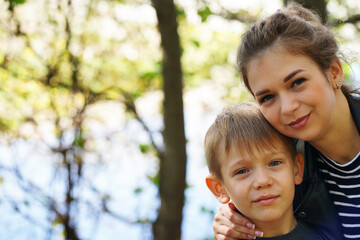 Portrait of mother and her little son on walk in countryside. Close up of young woman with child in nature.