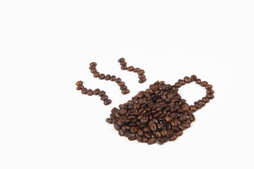 Roasted coffee beans placed in the shape of a cup and saucer on white background