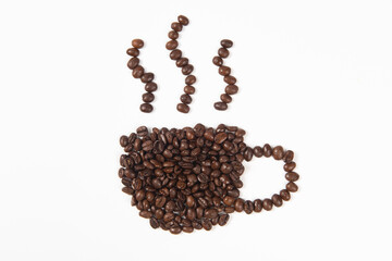 Roasted coffee beans placed in the shape of a cup and saucer on white background