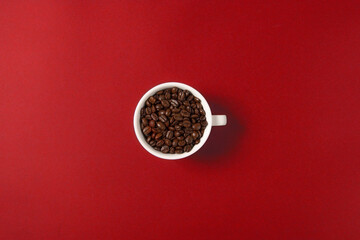 A cup of coffee  beans isolated on red background, top view