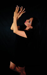 Obraz premium Mujer latina muy elegante mirándose las manos con vestido negro en una estudio fotográfico