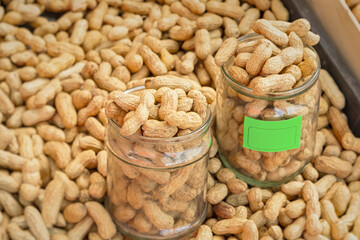 Peanuts in the shell are sold in the market. The measure of weighing with a glass jar. Close-up, full frame. The concept of harvesting, producing and growing nuts. Healthy products, fresh, delicious.