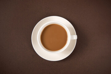 A cup of coffee isolated on brown background, top view