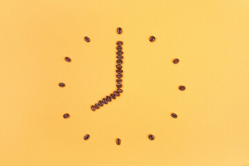 Coffee beans conventionalized to clock  on yellow background