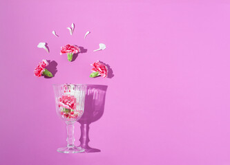 Spring colorful flowers in a wine glass on bright lilac background. Minimal spring concept. Nature background idea.