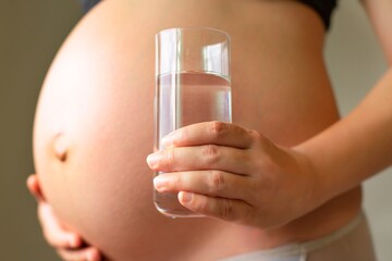 A healthy pregnant woman drinking a glass of water. Prenatal care and diet.
