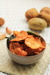 Selected Focus Homemade Kering Kentang Balado or Spicy Sweet Crispy Potato with Caramelized Spice. Using Lime Leaf for Aromatic Spice. Served on Grey Bowl, White Background