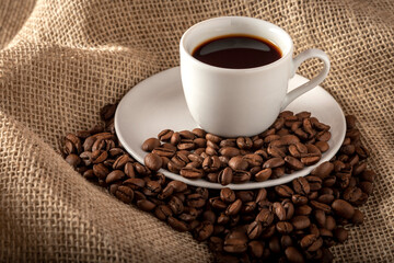cup of coffee with beans on jute